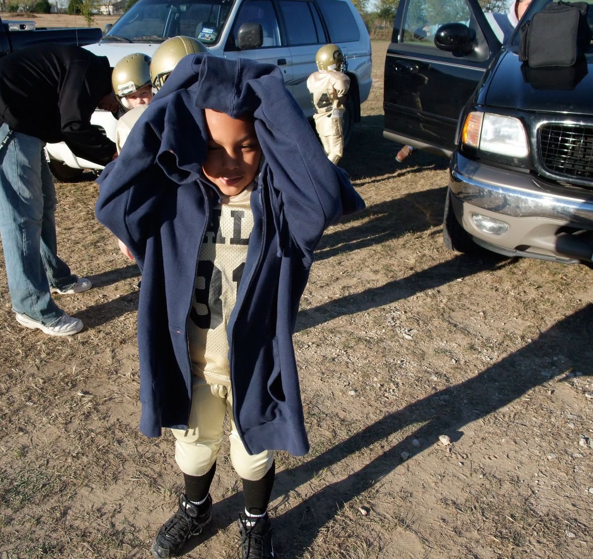 Image: Staying Warm — C.C. Jones raises his hood to reveal his game face before taking the field against the Scurry Rosser Wildcats.