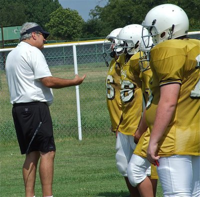Image: Step one — Line coach Stephen Coleman directs the “bigs” on proper blocking assignments.