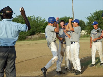 Image: Slap hands! — Teammates welcome Jacob Peterson home after his fence clearing, 3-run homerun.