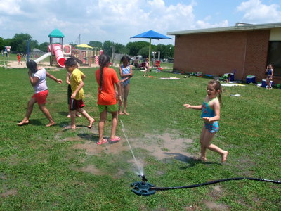 Image: Sprinkler Fun — These students are running from the sprinkler…kinda.