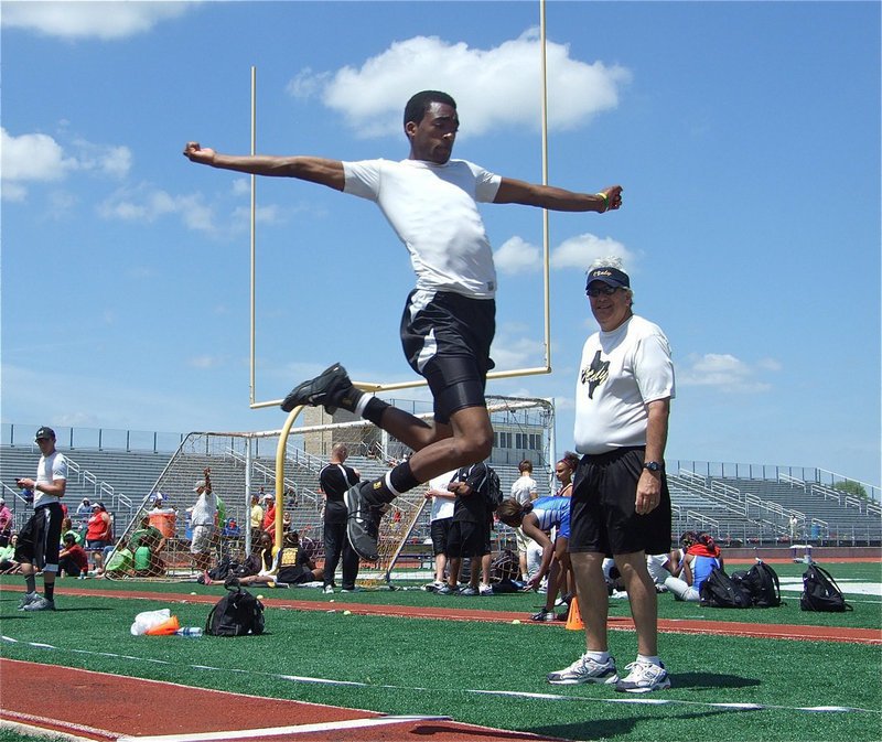 Image: Heath Clemons glides on air to place in the triple jump — Coach Stephen Coleman watches in amazement as Heath Clemons proves that “I” can fly during the Area track meet held at Charles Head Stadium on Alvarado High School campus. Clemons placed 3rd in the event to advance to Regional in May.