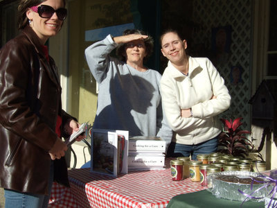 Image: Cookbooks and Candles too — Jenna Chambers, Karen Mathiowetz and Kelly Svehlak (Silver Bullets team members) all busy selling baked goods, candles and cookbooks all in the effort of raising money for the American Cancer Society.