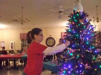Image: Putting on the Angel — Darla put the angel on the tree in memory of Cordell Clanton.