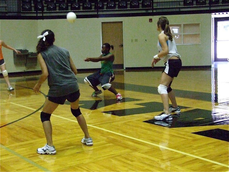 Image: Brianna gets low — Brianna Burkhalter gets low to lift the ball as Anna Viers and Brianna Perry observe.