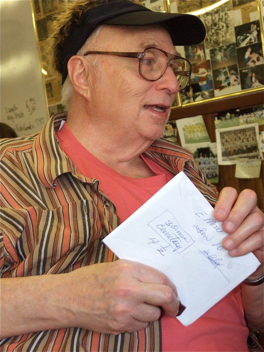 Image: Opening cards — Sporting a party hat that makes him look 10 years younger, Ervin opens a few of his birthday cards during his 80th birthday party.