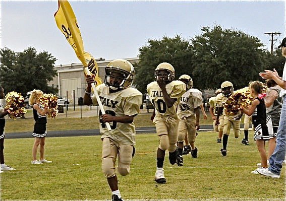 Image: Charge! — Tyvon Gates(40) and Taron Smith(10) lead the IYAA B-Team Gladiators (3rd &amp; 4th graders) into Hubbard’s stadium as the IYAA Cheerleaders cheer them on!