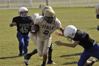 Image: Keeper play — IYAA A-Team quarterback Tylan Wallace(2) stiff-arms his way thru a Bulldog defender.