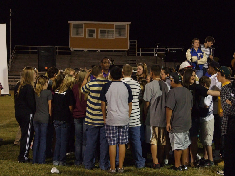 Image: Rev. Muse — In the center of the students, Rev. Mittie Muse explains the challenge.