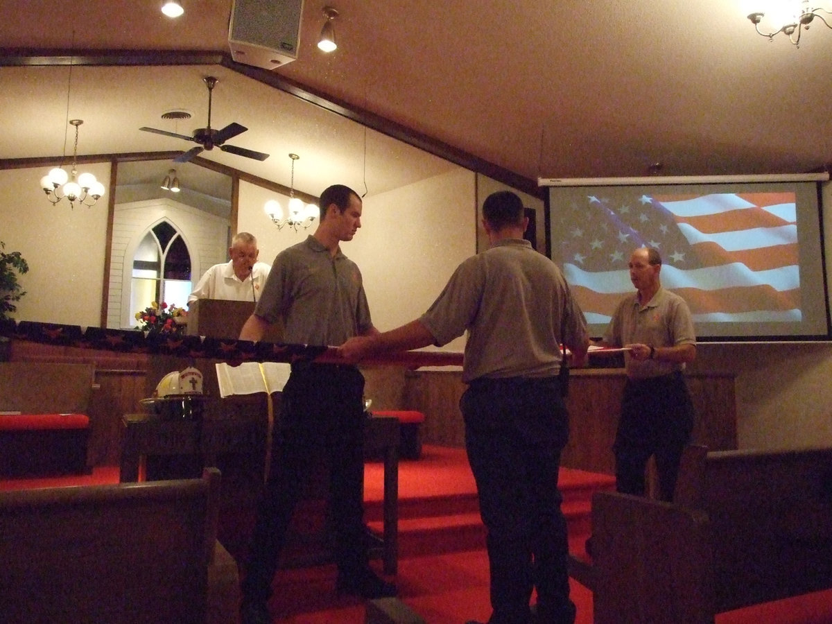 Image: Local firefighters show the symbolism — Tommy Sutherland, Eric Bradley, Russell Coers and Josh Droll prepare for the flag ceremony.