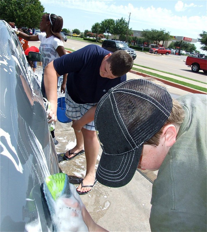 Image: Humming while working — IHS Band members Kortnei Johnson, Zachary Mercer and Brett Kirton scrub-a-dub the cars.