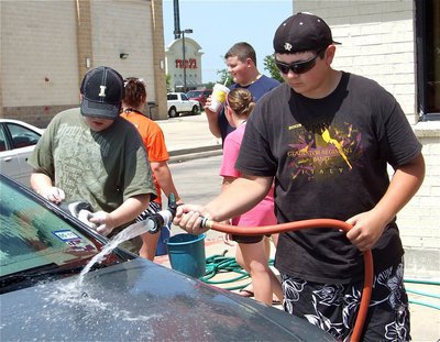 Image: It takes two — Kevin Roldan mans the hose while Brett Kirton soaps the side view mirror.
