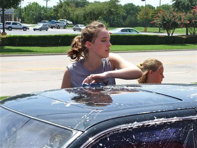 Image: Perfect harmony — Melissa Smithey uses her height to clean the car tops while Makenzie Davis-Goodwin soaps the sides.