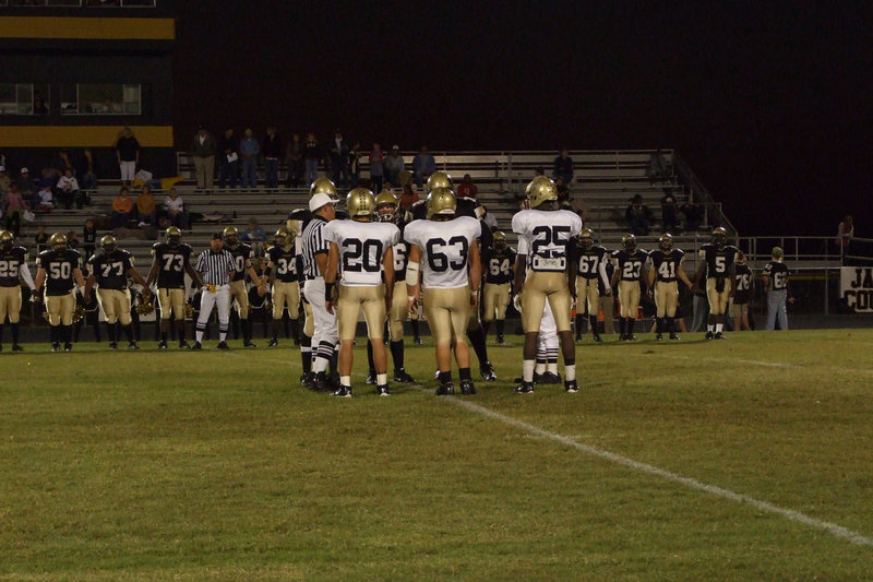 Image: Captains meet in middle — #20-Clay Major, #63-Zach Hernandez and #25-Diamond Rogers listen to the referees.
