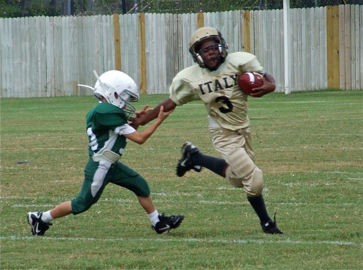 Image: Run, Ricky, run! — IYAA Minors running back Ricky Pendleton(3) fights off a Wildcat defender.