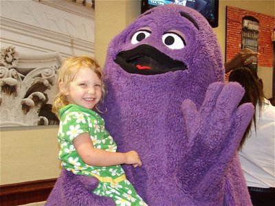 Image: Hannah and Grimace — Hannah Harris gets her picture taking with Grimace at McDonald’s in Italy during IYAA Sports Night.