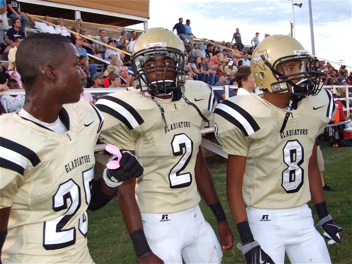 Image: I got an idea! — Corrin Frazier(25), Heath Clemons(2) and Eddie Garcie(8) formulate a plan on the sideline.