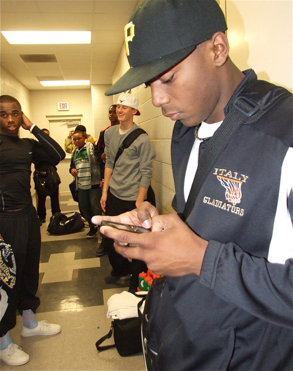 Image: Texting the world — Senior Desmond Anderson gets the word out that the Italy Gladiators beat Itasca 73-61 to claim the district championship.