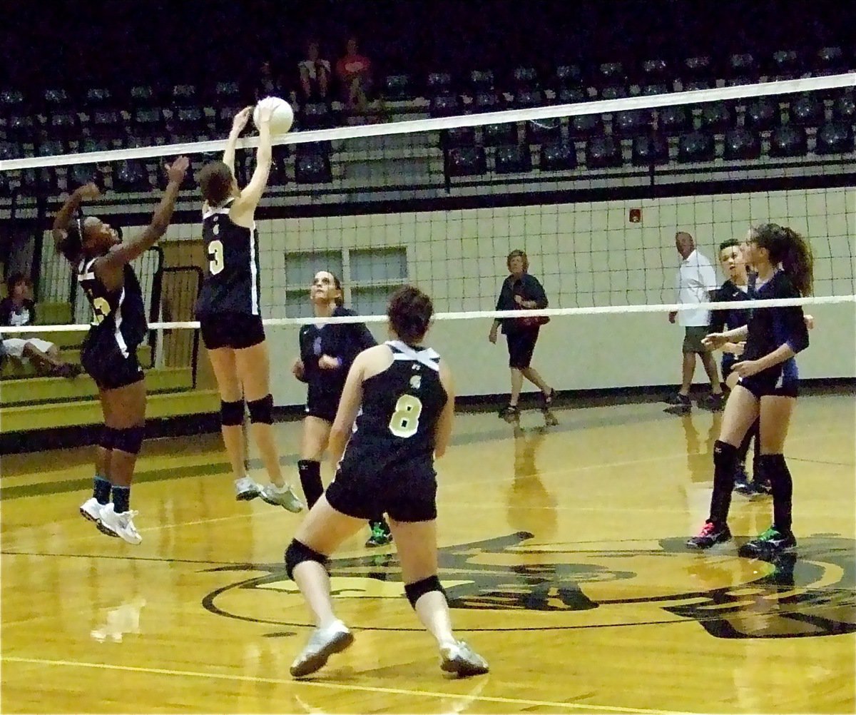 Image: Another level — Brianna Burkhalter(13) and Kaitlyn Rossa(3) overpower Rice at the net as Bailey Bumpus(8) rushes in to assist.