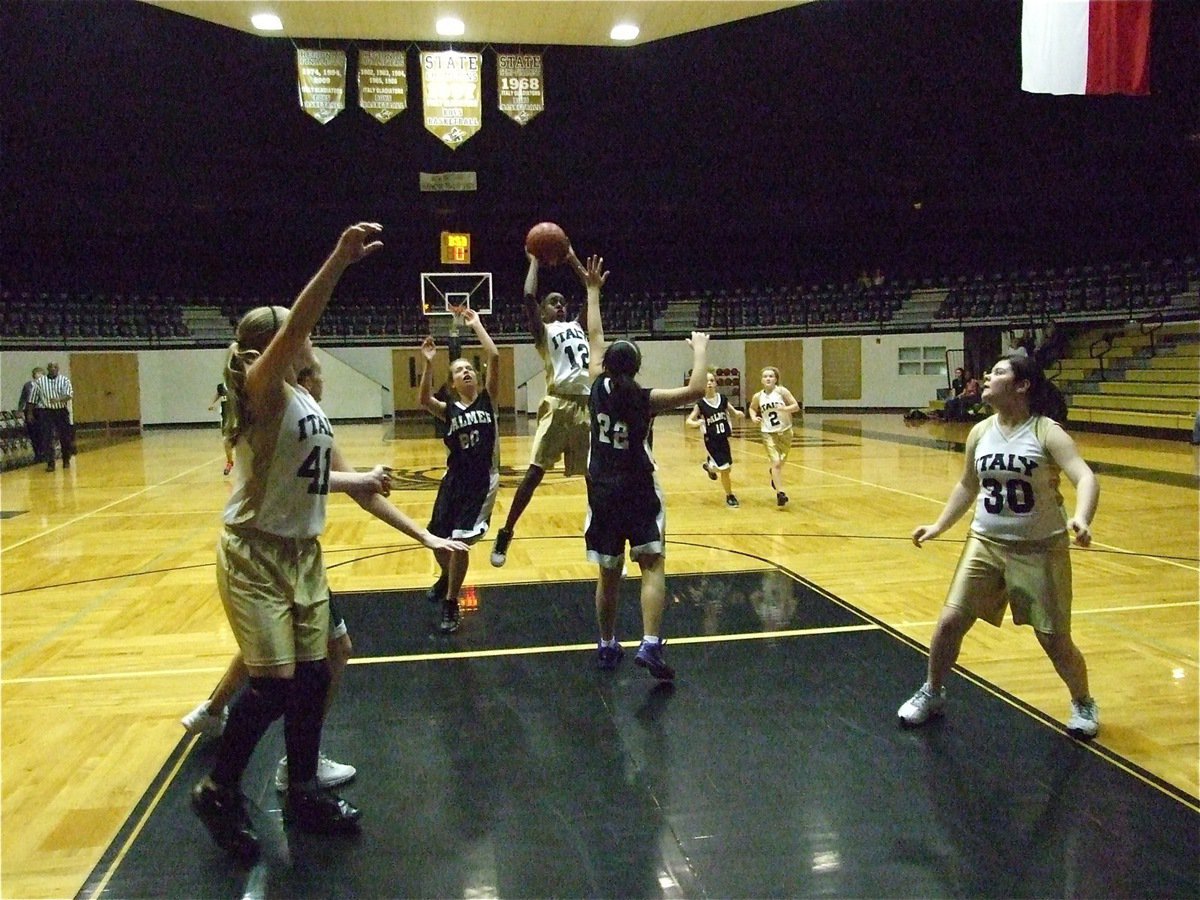 Image: Kortnei leaps — Kortnei Johnson(12) leaps above the Palmer defense as Jaclynn Lewis(41) and Bailey DeBorde(30) get in position to receive the pass.