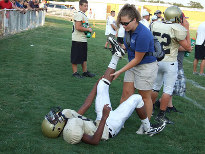 Image: Stretching the muscles — Melissa, volunteer trainer from Baylor Medical in Dallas, helps Trevon Robertson with his cramps.