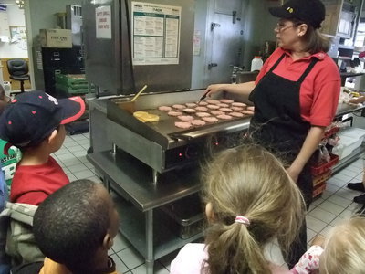Image: Here are the Burgers! — Sherry Phillips (manager) gives the kids lessons cooking hamburgers.