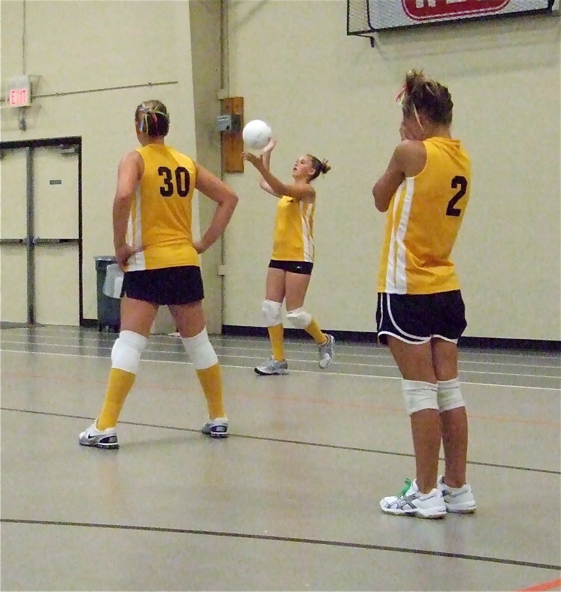 Image: With the game intensifying, Kelsey Nelson serves while Madison Washington(30) and Bailey Eubank(2) hope for the best.