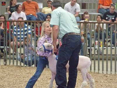 Image: Lacy Mott — Lacy Mott controls her lamb while looking, smiling and listening to the judge.