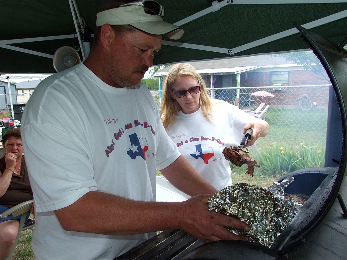 Image: Ain’t got a Clue? — Italy’s Brian and Darla Morgan of Ain’t Got a Clue BBQ get ’er done on the grill.