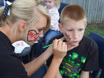 Image: Face painting — Sierra Harris paints the elementary student’s face.
