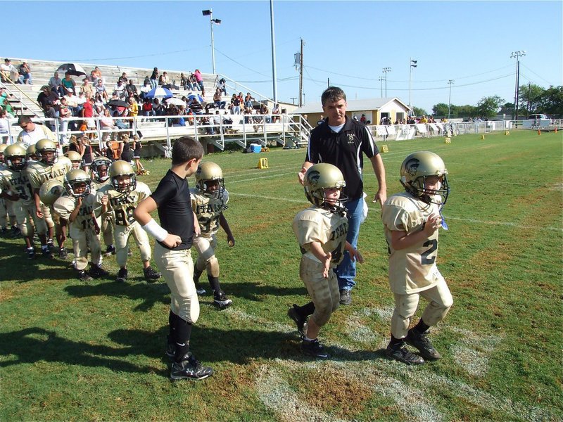 Image: The walk of victory — C-team head coach Gary Wood, with help from Gary Escamilla, directs his players across the field to congratulate Blooming Grove on a hard fought game.