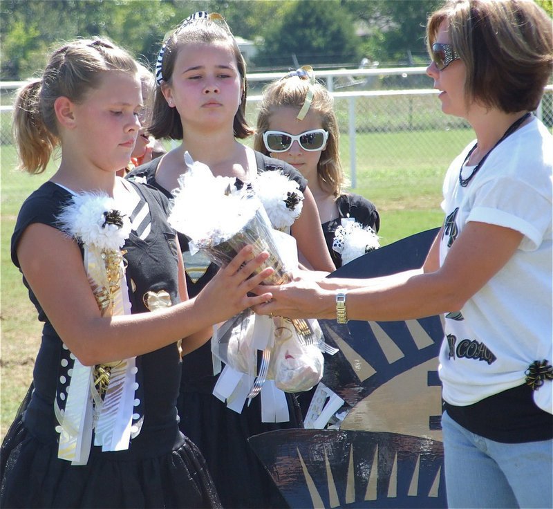 Image: Cheerleaders get a well deserved applause — Lilly Perry receives flowers and gifts from cheer coach Darla Wood as fans cheer for the cheerleaders.