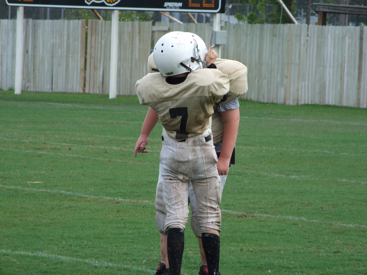 Image: We’re in this together — All for one and one for eleven. Quarterback  J.T Escamilla (7) tries to keep his offensive lineman in working condition as he snaps the headgear on teammate James Prator.