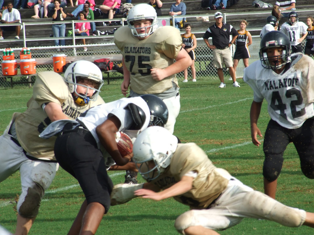 Image: Tackling a Tiger — John Byers (54), Tyler VinCell(75) and Colton Petry(6) try to put the clamps on the Tigers.