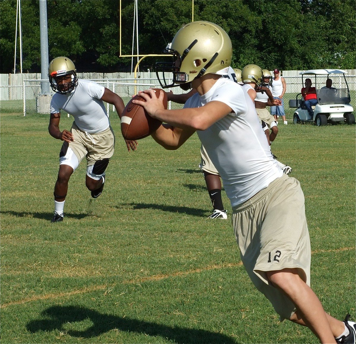 Image: J.V. quarterback Tony Wooldridge(12) rolls out with Jasenio Anderson in hot pursuit.