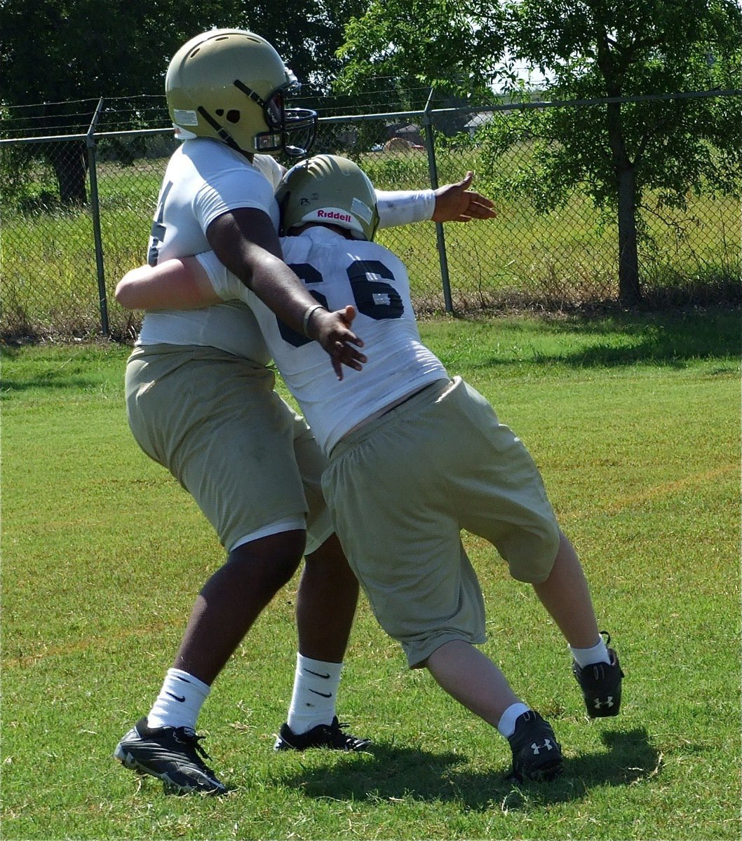 Image: Practice before pads — Jake Escamilla(66) works on form tackling with Bobby Wilson. On Friday, they’ll run these tackling drills in full pads.