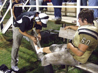 Image: Ivan hurts — Coach Kyle Holley tapes Ivan Roldan’s ankle during the game.
