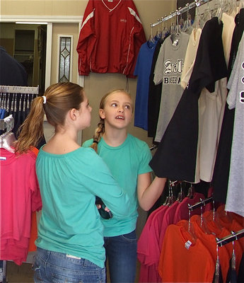 Image: I want it! — Annie Perry and Brooke DeBorde admire a pre-printed Italy softball shirt hanging inside the new Game On Athletics print shop.