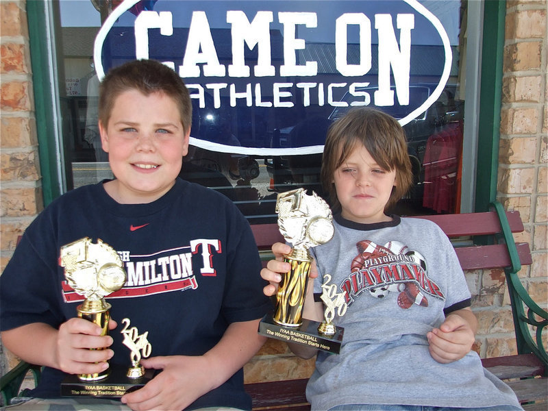 Image: Cade and Cason — The Roberts brothers show off their IYAA Basketball trophies while relaxing in front of the Game On Athletics sign. Game On Athletics and the IYAA teamed up during the store’s grand opening event.