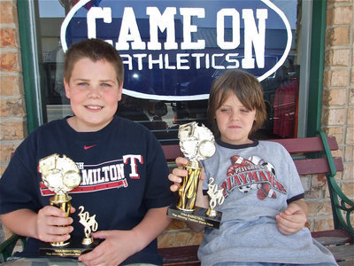 Image: Cade and Cason — The Roberts brothers show off their IYAA Basketball trophies while relaxing in front of the Game On Athletics sign. Game On Athletics and the IYAA teamed up during the store’s grand opening event.