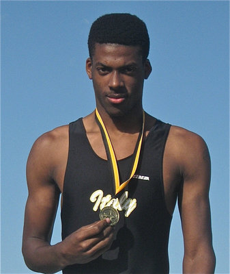 Image: John on the podium — John Isaac displays his medal while standing on the podium.