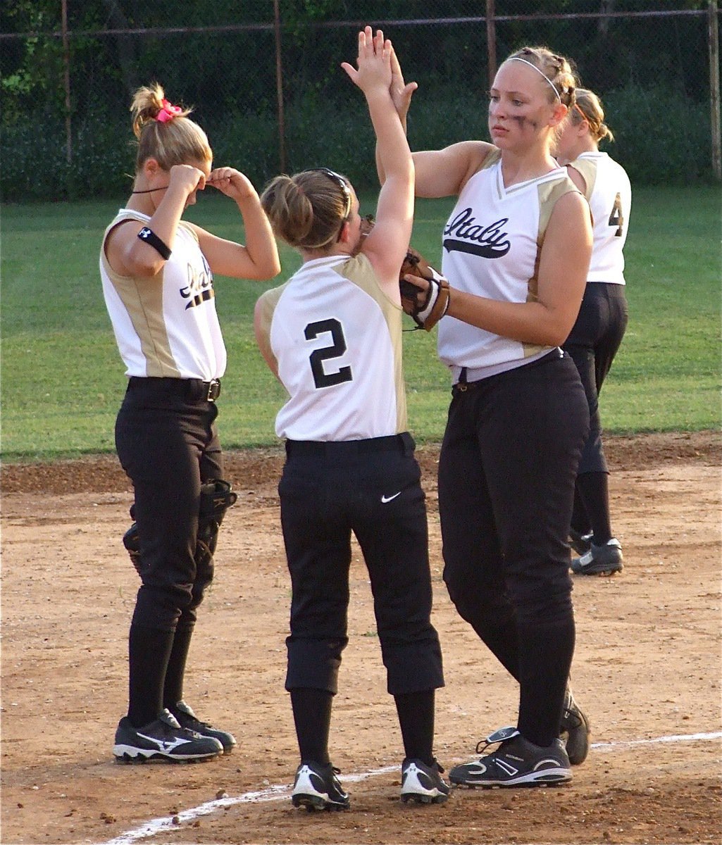 Image: Nice job — Tara Wallis high fives pitcher Jaclynn Lewis while Bailey Eubank makes an equipment adjustment.