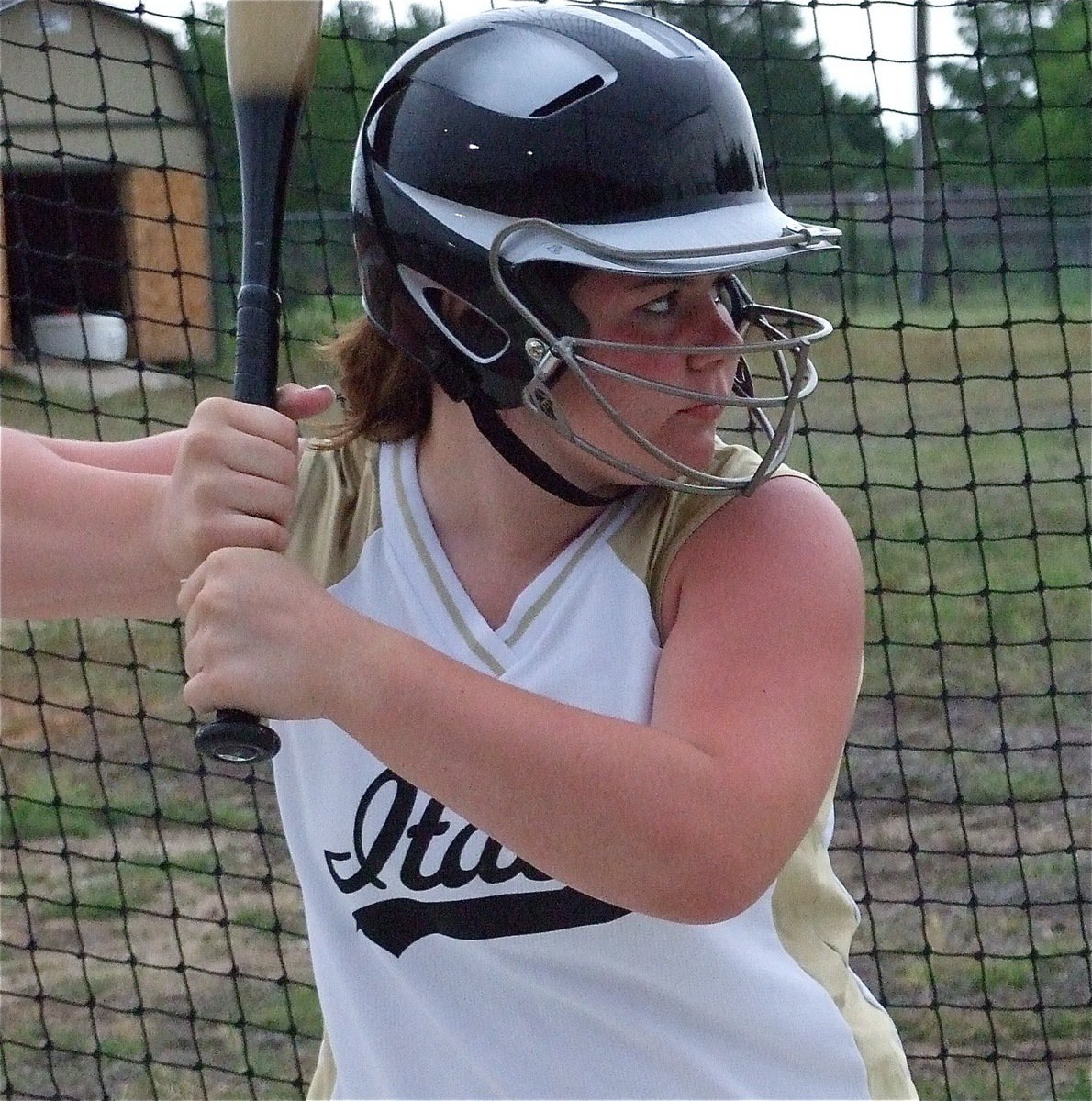 Image: DeBorde in the cage — Bailey DeBorde takes a few practice swings in the batting cage before the Itasca game.