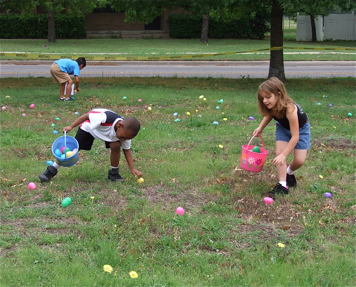 Image: There’s one! — Eager Egg hunters fill their baskets while spotting eggs covering the Dunlap Memorial Library’s front lawn.