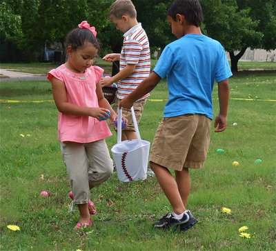 Image: A little help — Veronica Snyder gets a helping hand from her big brother, Nicolas Snyder, during the Easter Egg hunt while Taylor Sparks keeps collecting eggs in the background.