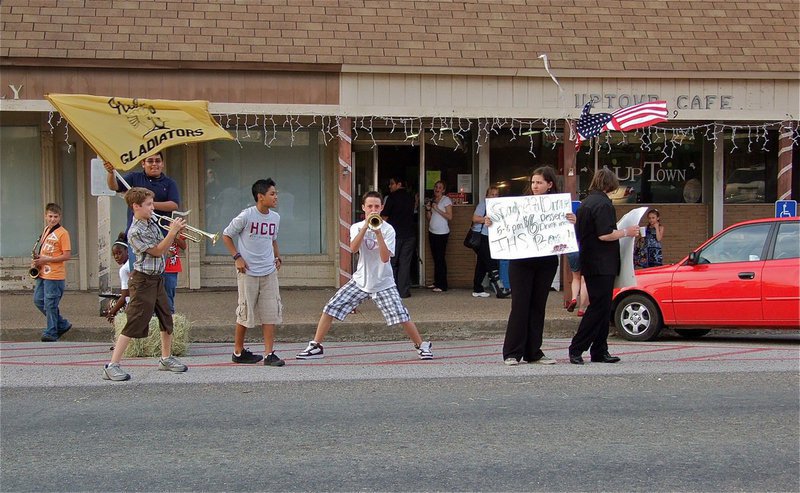 Image: Gladiator Regiment Band members invite travelers in for spaghetti — Pedro Salazar waves the Italy Gladiator flag while Brandon Connor, Carl Jaynes, Fabian Cortez, Jordan Lemire, Alexis Sampley and Trevor Davis convince Main Street travelers to stop in for a spaghetti dinner as part of the Gladiator Regiment Band’s fundraiser to take a group trip to Florida.