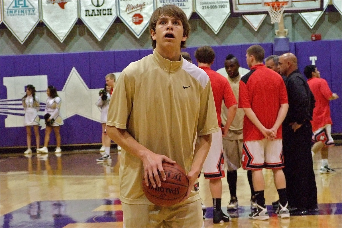 Image: Young gun — Sophomore Cole Hopkins practices a free-throw while team captain Jasenio Anderson meets with the Cardinal captains.