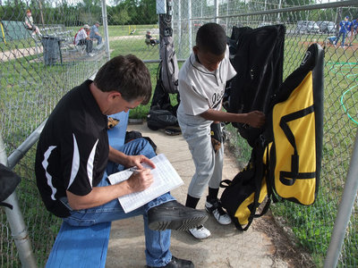Image: Dotting their i’s, crossing their t’s and zipping their gear up are Coach Gary Wood and shortstop Eric “Flash” Carson as they get prepred to begin the season.