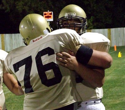 Image: Group hug — Two defensive linemen qualifies as a group. Hank Seabolt(76) congratulates Kevin Roldan(60) after his strip and sprint that put the Gladiators in scoring position.