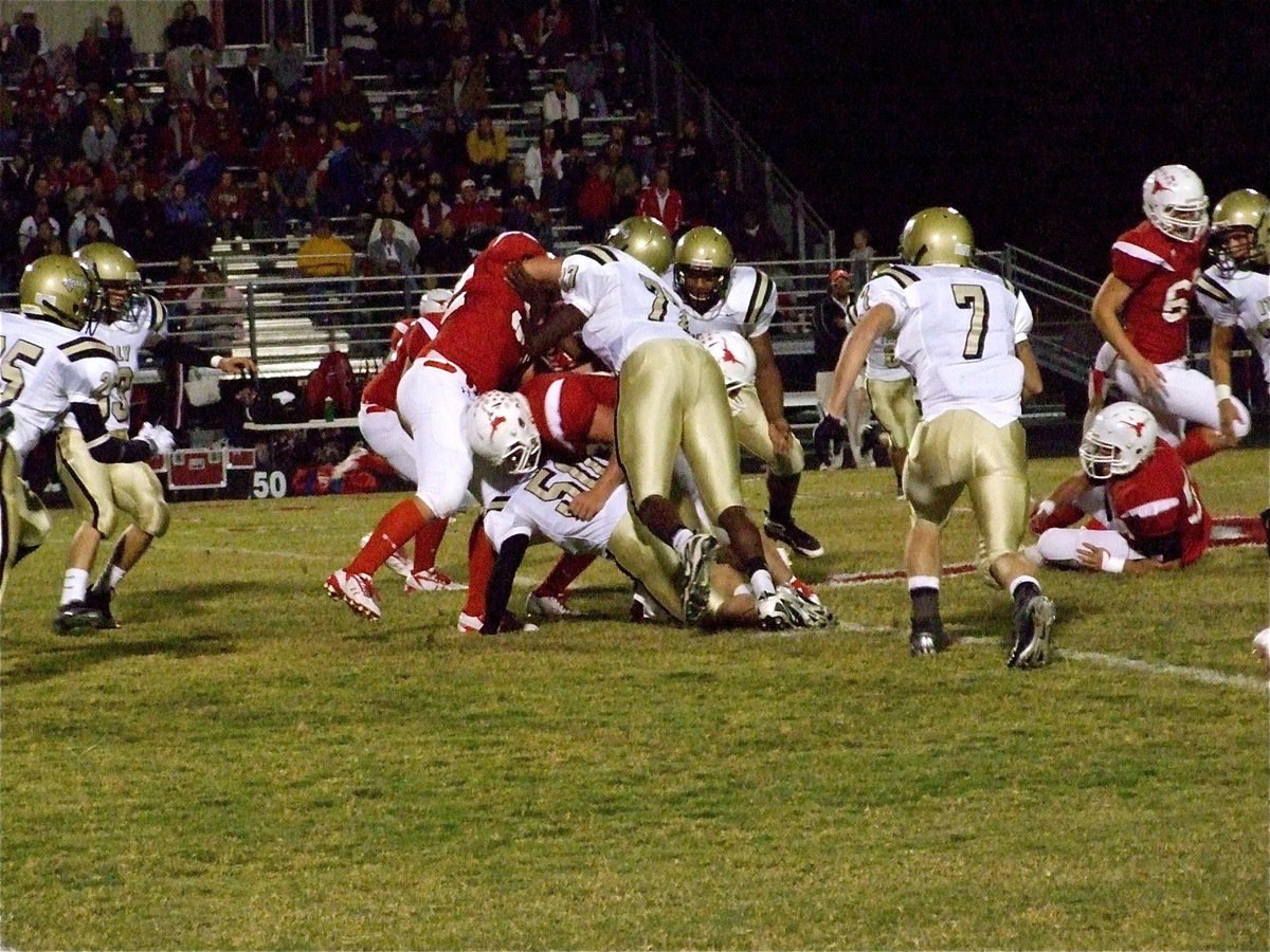 Image: Ground attack — Ethan Simon(50), Larry Mayberry(77), De’Andre Rettig(6) and Kyle Wilkins(7) try to locate the Axtell runner.