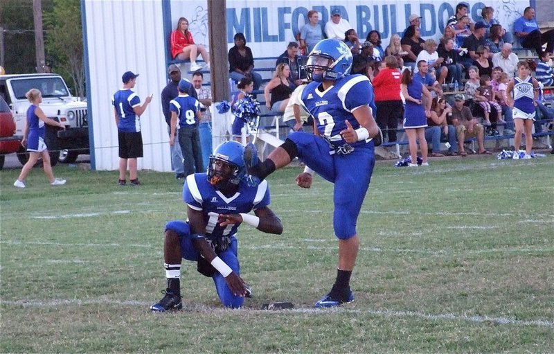 Image: It’s up and it’s good! — Ernest Lee Smith(11) holds while kicker Rolando Vega(2) boots thru a 2-point kick during the Milford Bulldogs’ 2010 Homecoming victory over the Walnut Springs Hornets, 52-6